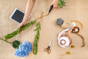 cropped shot of female florist with secateurs cutting stem while arranging plants